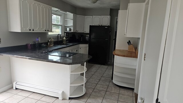 kitchen with sink, black appliances, white cabinets, light tile patterned flooring, and kitchen peninsula