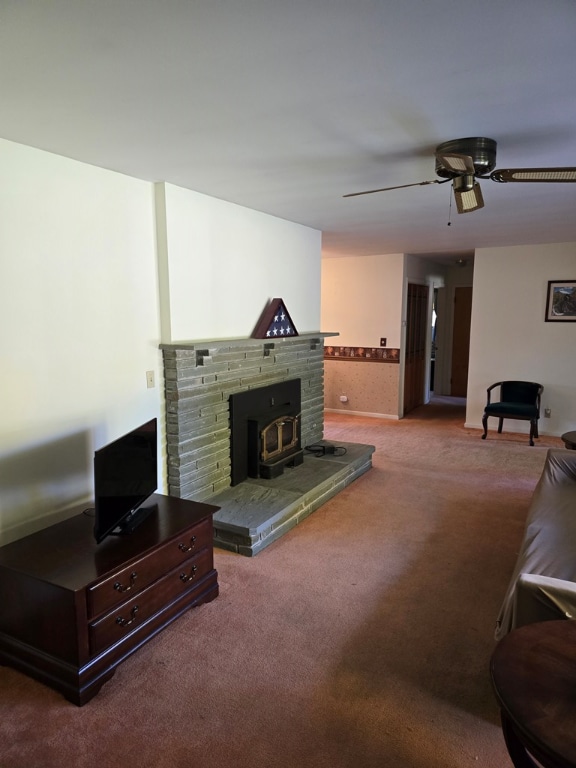 carpeted living room with ceiling fan and a wood stove