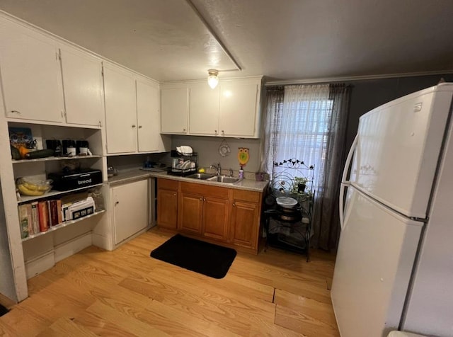 kitchen with white refrigerator, white cabinetry, sink, and light hardwood / wood-style flooring