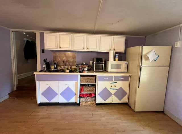 kitchen with sink, white appliances, light hardwood / wood-style floors, and white cabinets