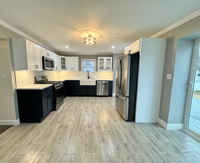 kitchen with sink, crown molding, stainless steel appliances, tasteful backsplash, and white cabinets