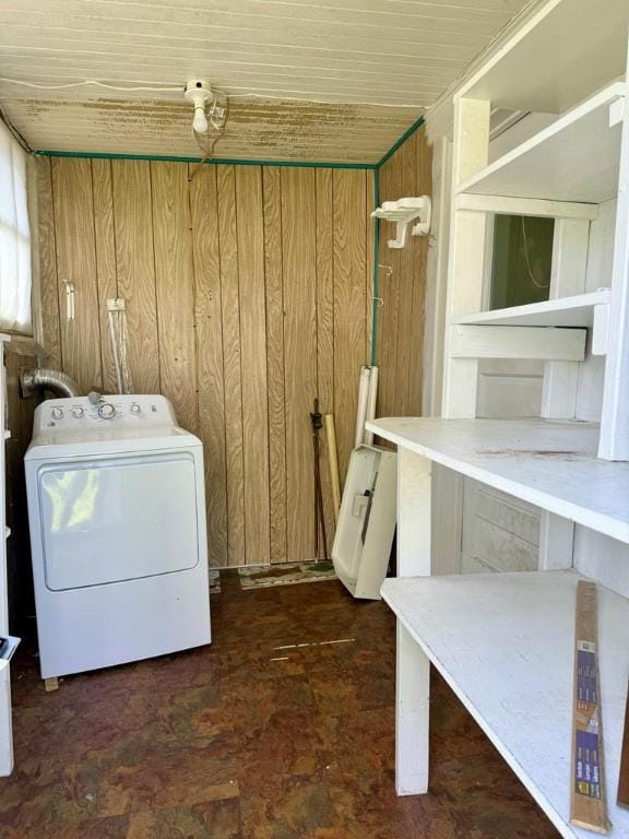 clothes washing area with washer / clothes dryer and wooden walls