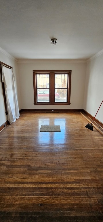 empty room featuring wood-type flooring and ornamental molding