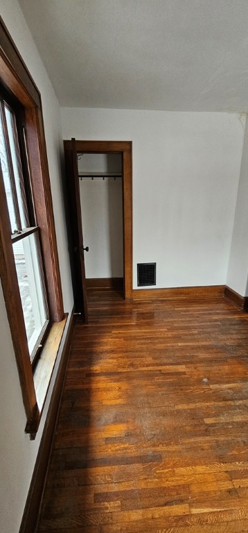 unfurnished bedroom with dark wood-type flooring and a closet