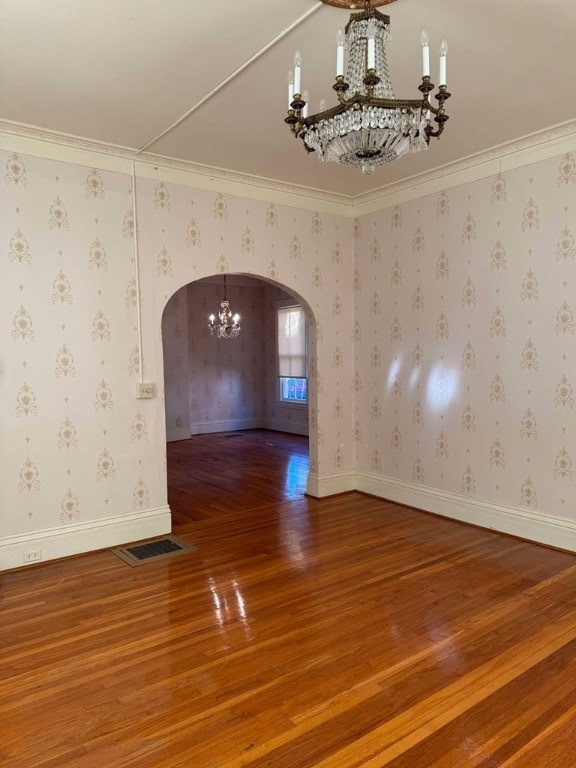 unfurnished room featuring ornamental molding, wood-type flooring, and an inviting chandelier