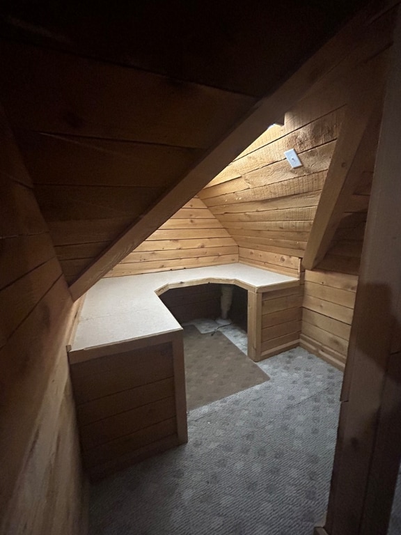 additional living space with light carpet, wooden walls, and vaulted ceiling