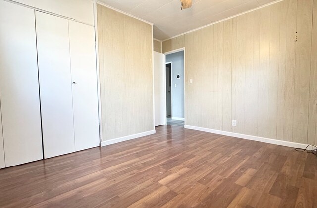 unfurnished bedroom with crown molding, wood-type flooring, and a closet