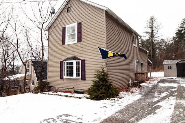 view of snowy exterior featuring a storage shed