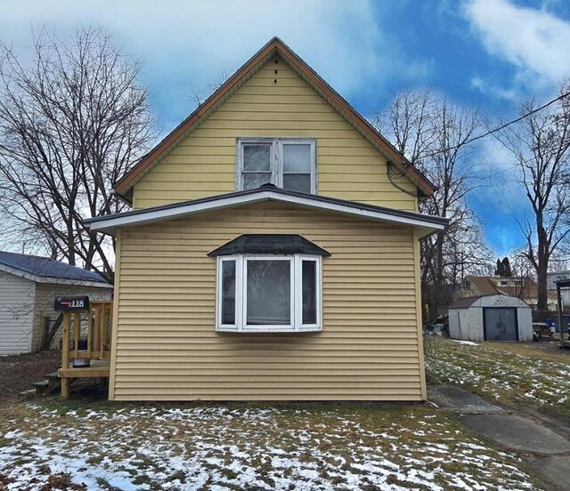 view of snowy exterior featuring a storage shed