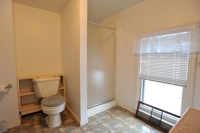 bathroom featuring toilet and a shower with shower door