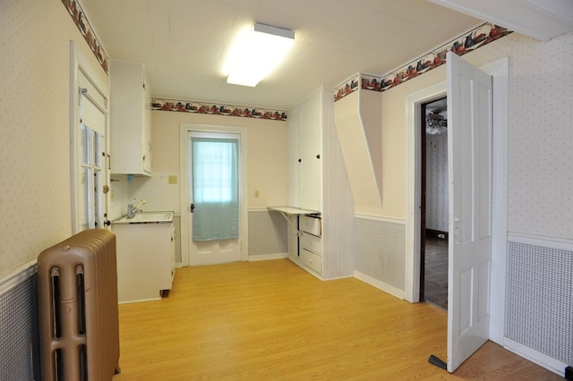 laundry room with radiator heating unit and light hardwood / wood-style floors