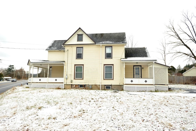 snow covered rear of property with a porch