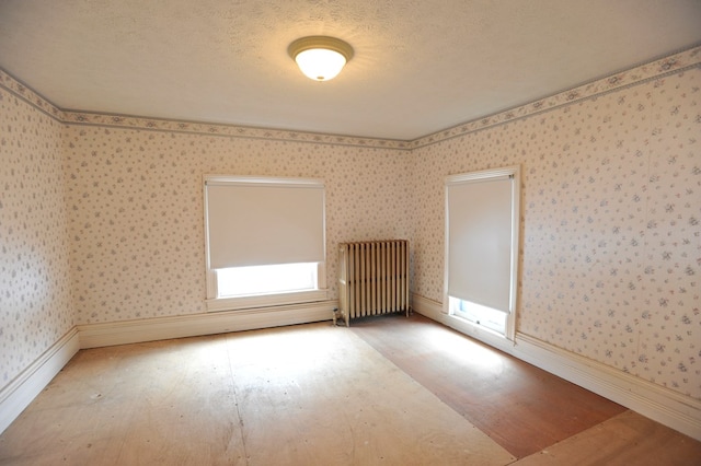 spare room featuring hardwood / wood-style flooring, radiator, and a textured ceiling