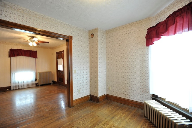 unfurnished room with ceiling fan, radiator heating unit, dark hardwood / wood-style floors, and a textured ceiling