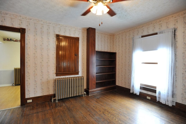 unfurnished living room featuring dark wood-type flooring, radiator, and a textured ceiling