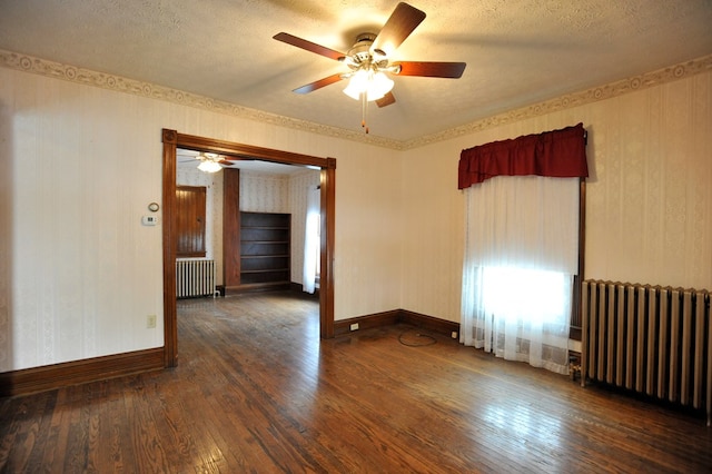 empty room with dark wood-type flooring, ceiling fan, radiator heating unit, and a textured ceiling