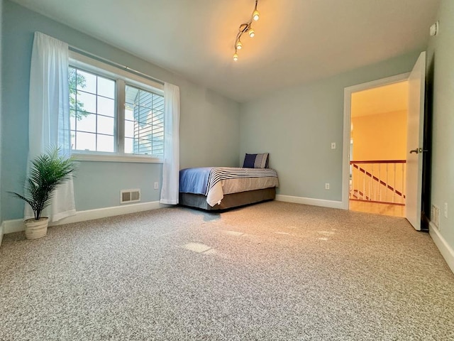 unfurnished bedroom with rail lighting and carpet flooring