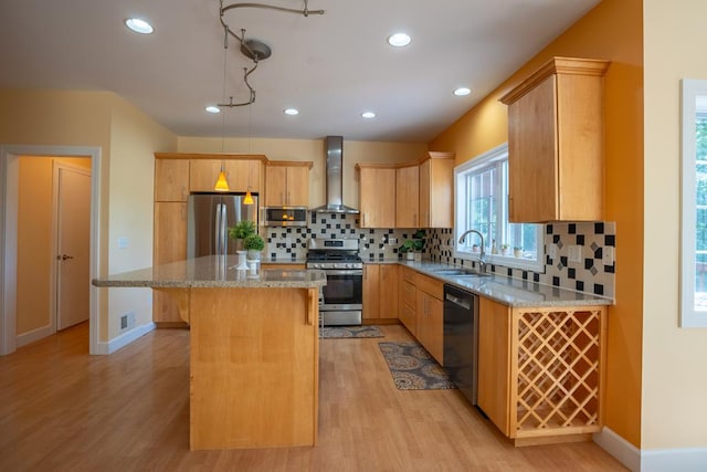 kitchen featuring a kitchen island, appliances with stainless steel finishes, sink, light stone counters, and wall chimney range hood