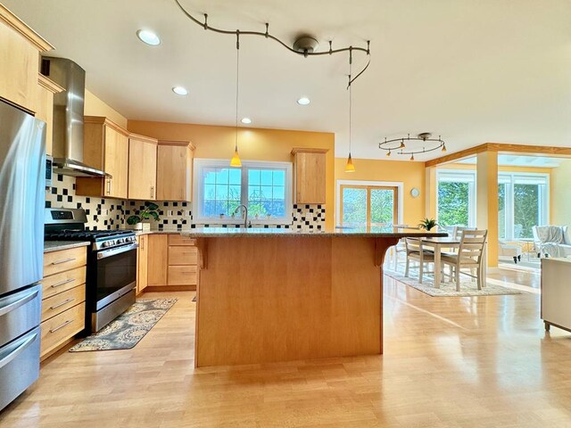 kitchen with appliances with stainless steel finishes, decorative light fixtures, light brown cabinetry, and range hood