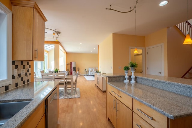 kitchen featuring tasteful backsplash, light hardwood / wood-style flooring, hanging light fixtures, light brown cabinets, and stainless steel dishwasher