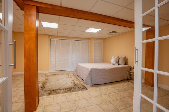 bedroom with multiple closets and a paneled ceiling