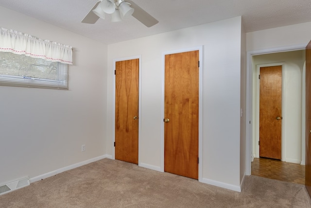 unfurnished bedroom with ceiling fan, light carpet, and a textured ceiling