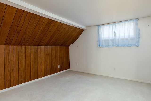 bonus room featuring wooden walls, vaulted ceiling, and light carpet