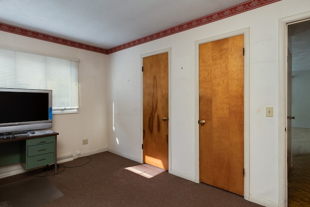 unfurnished office with a textured ceiling and dark colored carpet