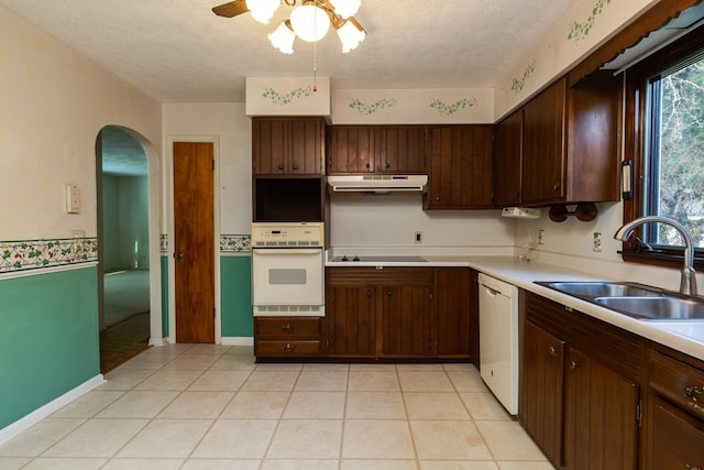 kitchen with sink, light tile patterned floors, white appliances, dark brown cabinetry, and a textured ceiling