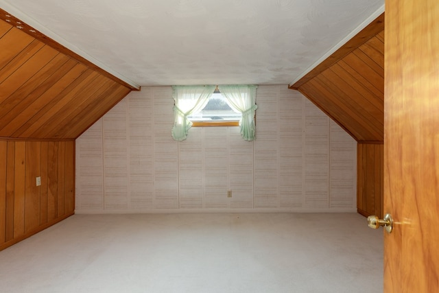 additional living space with vaulted ceiling, carpet, and wood walls