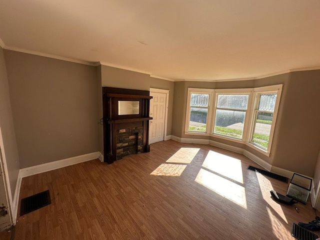 interior space with hardwood / wood-style floors, a stone fireplace, and ornamental molding