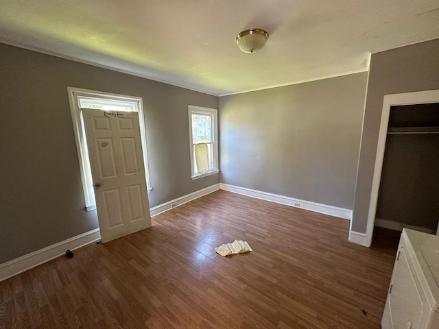 unfurnished bedroom featuring dark hardwood / wood-style flooring, ornamental molding, and a closet