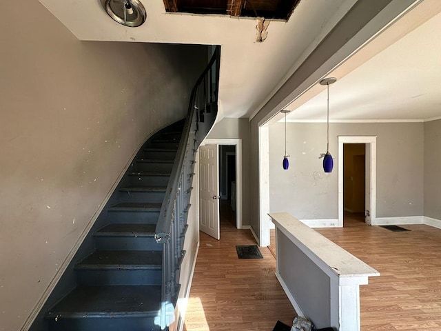 staircase featuring crown molding and wood-type flooring