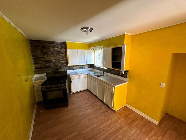 kitchen with sink, crown molding, stainless steel stove, backsplash, and wood-type flooring