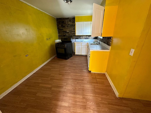 kitchen with hardwood / wood-style floors, sink, black range with gas stovetop, decorative backsplash, and crown molding