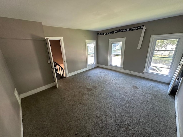 unfurnished bedroom featuring multiple windows and dark colored carpet