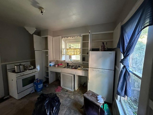 kitchen with sink, white stove, white cabinetry, fridge, and tile counters