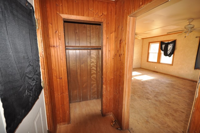 hall with hardwood / wood-style flooring and wood walls