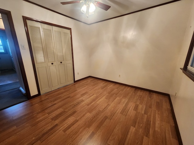 unfurnished bedroom with hardwood / wood-style floors, ornamental molding, a closet, and ceiling fan