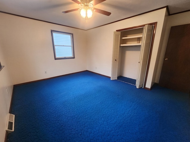 unfurnished bedroom featuring ornamental molding, a closet, ceiling fan, and dark colored carpet