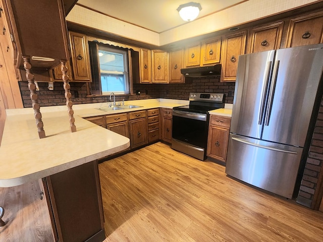 kitchen with appliances with stainless steel finishes, kitchen peninsula, and light hardwood / wood-style flooring