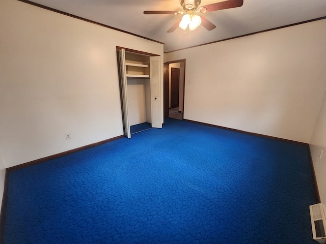 unfurnished bedroom with dark carpet, ornamental molding, a closet, and ceiling fan