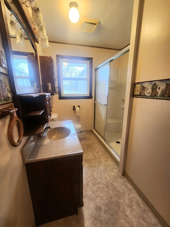 bathroom featuring an enclosed shower, vanity, toilet, and a healthy amount of sunlight