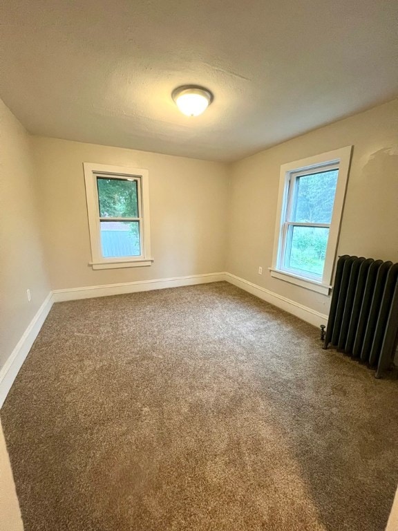 carpeted empty room featuring radiator and a textured ceiling