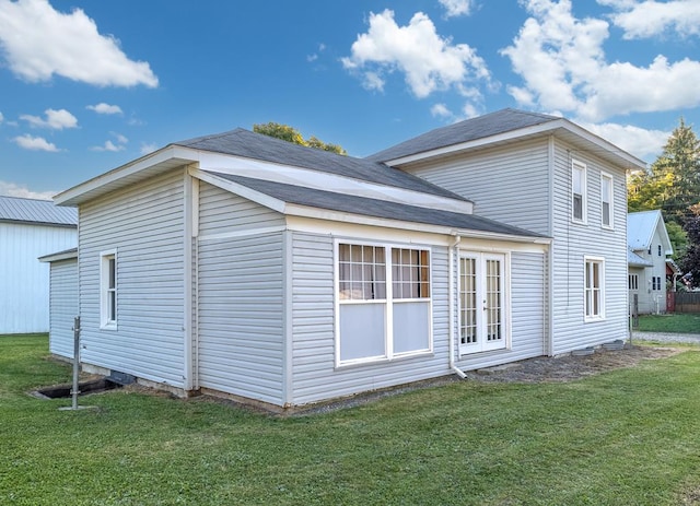 view of property exterior with french doors and a lawn