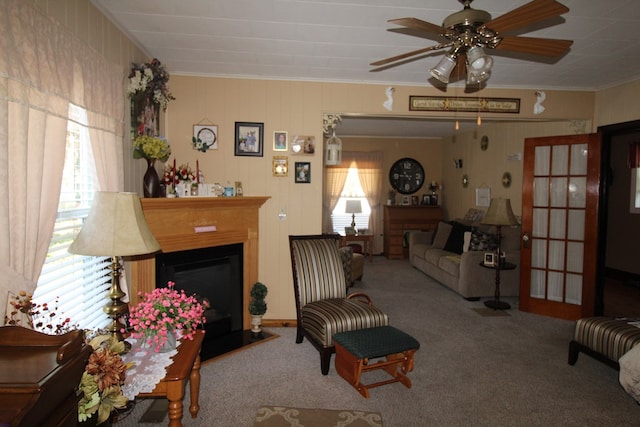 living room with ceiling fan, ornamental molding, and carpet flooring