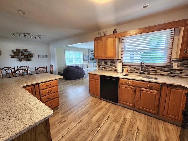 kitchen with tasteful backsplash, light wood-style floors, brown cabinetry, a sink, and dishwasher