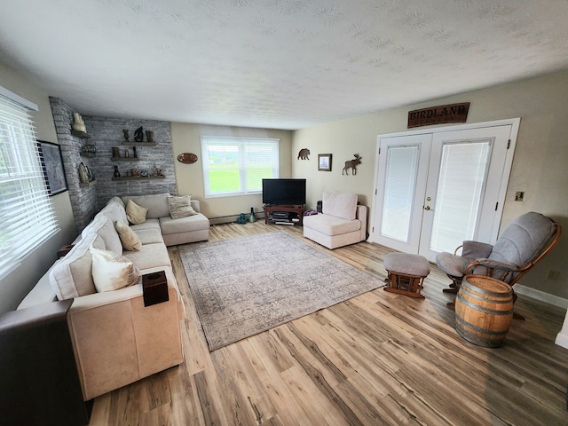 living room with a textured ceiling, french doors, wood finished floors, and baseboards