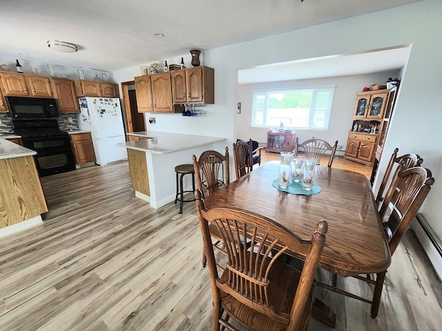 dining area with a baseboard radiator and light wood-type flooring