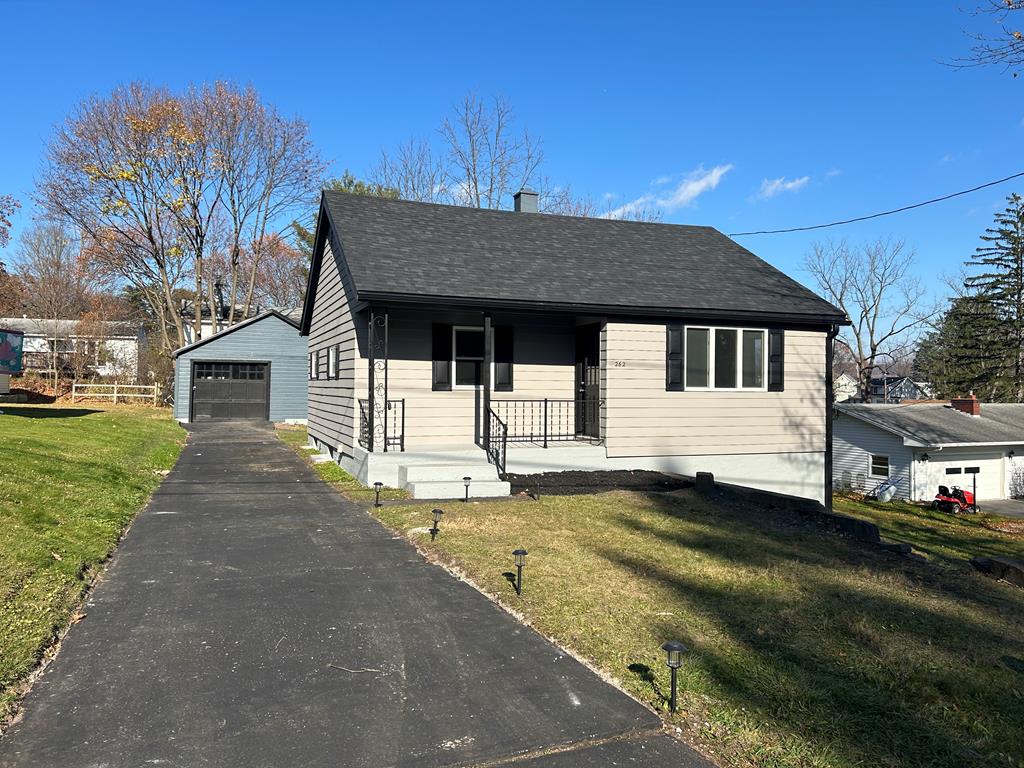 view of front of home featuring a garage, an outdoor structure, a front yard, and a porch